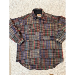 Pode incluir: Uma camisa de manga comprida com botões e um padrão xadrez multicolorido em tons de vermelho, azul, verde e amarelo. A camisa inclui um colarinho, dois bolsos no peito e uma etiqueta no interior do decote com a palavra Paragraph.