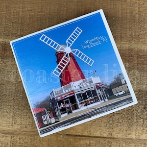 May include: A red and white windmill with a blue sky in the background. The windmill has a sign that says "Windmill Long Branch, NJ".