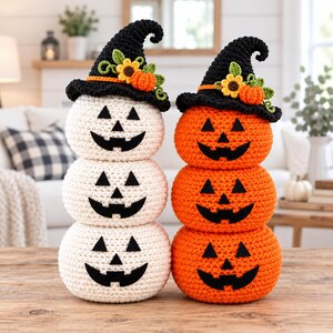 May include: Two stacked crochet pumpkin sets, one white and one orange, each featuring three pumpkins with black felt jack-o'-lantern faces. Both top pumpkins wear a black crocheted witch hat adorned with a small orange pumpkin and yellow sunflower.