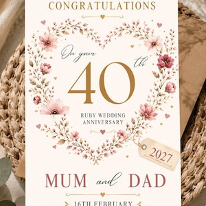 May include: A rectangular anniversary card featuring a heart-shaped floral wreath in shades of pink and brown. The text reads CONGRATULATIONS, On your 40th RUBY WEDDING ANNIVERSARY, MUM and DAD, 16TH FEBRUARY, and a small tag displays the year 2027.