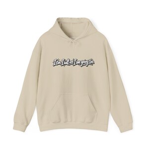 May include: A beige hooded sweatshirt featuring a front kangaroo pocket and long sleeves. The center of the chest displays the black and white text "I can, I will and I am going too." accented with small star graphics in a stylized script font.