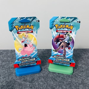 May include: Two Pokémon Trading Card Game booster packs titled Journey Together, each featuring distinct character illustrations. The left pack displays a blonde character and a pink Clefairy, while the right pack shows a character with a dark creature.
