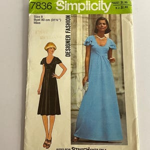 Op de afbeelding: Vintage Simplicity Designer Fashion naaipatroon, maat 8, borstomvang 80 cm. De envelop bevat illustraties van twee jurken: een zwarte knielange jurk en een lange blauwe jurk. De tekst op de envelop luidt "SIZED FOR STRETCH KNITS ONLY."