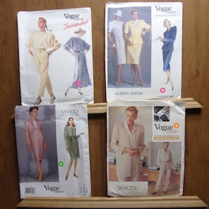 Puede incluir: Cinco patrones de costura vintage de Vogue con diferentes diseños. Los patrones son para un mono, un vestido con una chaqueta, un vestido con una chaqueta, un vestido con una chaqueta y una blusa con pantalones. Los patrones son todos en blanco con texto negro e ilustraciones.