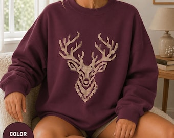 Könnte beinhalten: Ein kastanienbraunes Sweatshirt mit Rundhalsausschnitt und einer großen, mittigen Grafik eines Hirschkopfes, der aus kleinen, hellen Punkten besteht. Das Design zeigt das Geweih und die Gesichtszüge in einem geometrischen Stil.