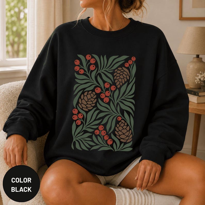 May include: A black crewneck sweatshirt featuring a central graphic print of stylized green foliage, brown pinecones, and clusters of red berries arranged in a rectangular pattern across the front of the garment.