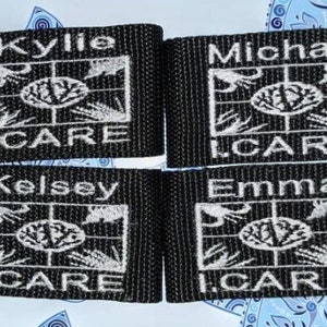 Puede incluir: Cuatro etiquetas de nombre de tela negra con texto bordado blanco y un logotipo. Se muestran los nombres "Kylie", "Michael", "Kelsey" y "Emma". Cada etiqueta también presenta el texto "I.CARE".
