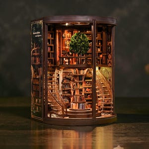 May include: A wooden book nook diorama featuring a multi-level library interior with a central tree, spiral staircases, and illuminated shelves. The structure includes detailed miniature books, a balcony, and the text Wisdom Wings Book Repository.
