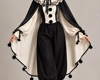May include: A black and cream jester costume featuring a cape with black pom-poms, a ruffled collar, and a matching hat. The outfit includes a fitted bodice with three black pom-pom buttons, loose-fitting trousers with ruffled cuffs, and black boots.