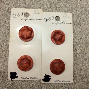 May include: Two cards of vintage brown buttons. Each card holds two round, star-shaped buttons. The cards are labeled "B.G.E. Originales" and "First in Fashions". The buttons are a reddish-brown color.