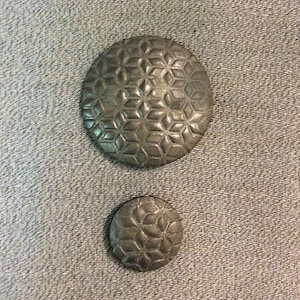 May include: Two silver buttons with a geometric pattern. The larger button is about 2 inches in diameter and the smaller button is about 1 inch in diameter.