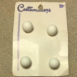 May include: A card with four white round buttons on it. The card says "Costumers" and "39¢" in blue lettering.
