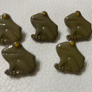 May include: Five brown frog buttons with yellow eyes. The buttons are about 1 inch in diameter.