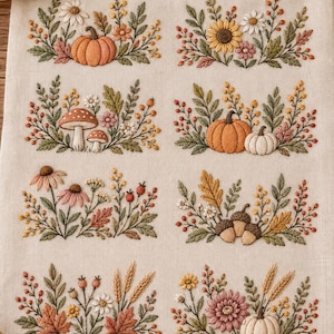 May include: A beige fabric panel featuring eight distinct embroidered autumn-themed motifs. The designs include pumpkins, mushrooms, sunflowers, acorns, wheat stalks, and various fall leaves and berries in shades of orange, yellow, and green.