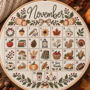 May include: A circular embroidery hoop featuring a November calendar with thirty numbered squares. Each square contains a stitched icon such as pumpkins, leaves, a turkey, a pie, and a football. The word November is stitched at the top.
