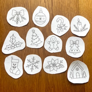 May include: A collection of twelve white fabric patches featuring black line art illustrations of holiday icons including a bow, ornament, candy cane, candle, holly, Christmas tree, gingerbread person, bell, stocking, snowflake, poinsettia, and house.
