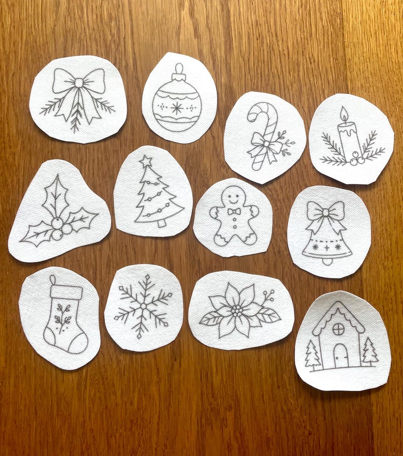 May include: A collection of twelve white fabric patches featuring black line art illustrations of holiday icons including a bow, ornament, candy cane, candle, holly, Christmas tree, gingerbread person, bell, stocking, snowflake, poinsettia, and house.