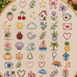 May include: A round wooden embroidery hoop containing off-white fabric with a grid of small, colourful hand-stitched icons. Designs include flowers, hearts, stars, a house, a sailboat, a rainbow, a cat, a bicycle, and various nature motifs.