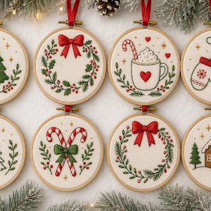 May include: Eight circular wooden embroidery hoops featuring festive holiday designs on white fabric. Patterns include a Christmas tree, a wreath with a red bow, a mug of cocoa, mittens, a decorated tree, candy canes, a second wreath, and a gingerbread house.