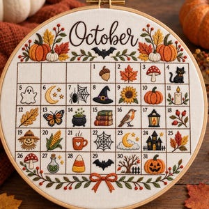 Pode incluir: Um bastidor de bordado redondo de madeira emoldurando um calendário de tecido branco para outubro. O design apresenta motivos de outono bordados à mão, incluindo abóboras, folhas, um gato preto, um fantasma, um chapéu de bruxa e uma abóbora.