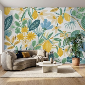 May include: A wall mural featuring a botanical pattern of yellow lemons, green leaves, and light blue and yellow flowers on a white background. The design is displayed behind a curved beige sofa, a white coffee table, and a potted plant.