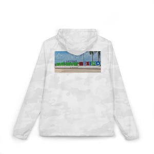 Puede incluir: Una chaqueta cortavientos con capucha y estampado de camuflaje blanco que presenta un gráfico rectangular en la espalda. La imagen muestra un letrero colorido con el texto "AQUÍ INICIA MÉXICO", palmeras y un cielo azul de fondo.