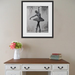 May include: A framed black and white drawing of a ballerina in a tutu, with a gray background. The drawing is signed "A. Thomas" in the bottom left corner.