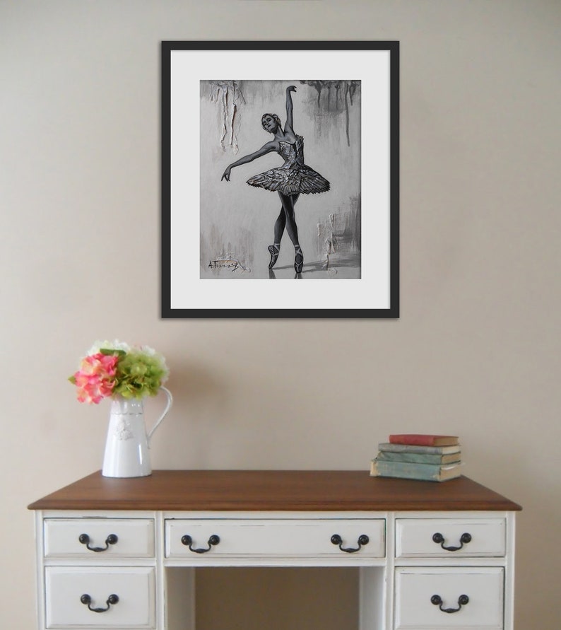 May include: A framed black and white drawing of a ballerina in a tutu, with a gray background. The drawing is signed "A. Thomas" in the bottom left corner.