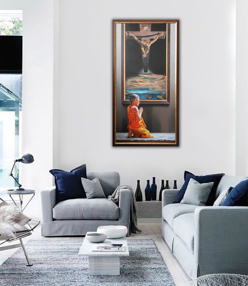 May include: A painting of a person kneeling in prayer in front of a framed image of a man on a cross. The person is wearing a yellow robe and the background is dark.