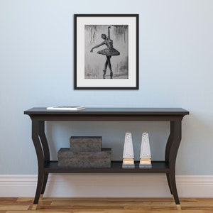 May include: A black and white framed print of a ballerina in a tutu, with a gray background.