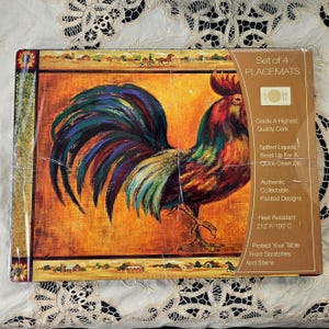 May include: A set of four rectangular cork placemats featuring a colorful rooster illustration against an orange background. The packaging includes text stating Set of 4 PLACEMATS, Grade A Highest Quality Cork, and Heat Resistant 212 F/100 C.
