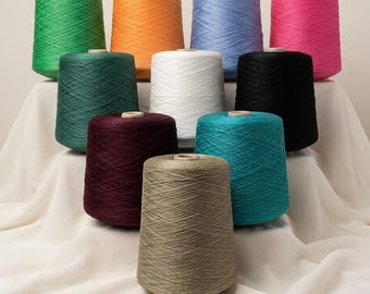 May include: A collection of ten conical spools of yarn arranged in a tiered formation. The colors include bright green, orange, light blue, hot pink, dark green, white, black, deep burgundy, teal, and a neutral beige-brown tone.