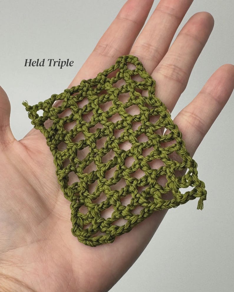 May include: A square swatch of olive green yarn featuring an open, net-like crochet stitch pattern. The text Held Triple is printed in black in the upper left corner of the image, indicating the yarn weight and technique used for this piece.