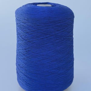 May include: A large cylindrical spool of vibrant royal blue yarn. The thread is tightly wound in a crisscross pattern around the central core, creating a uniform and dense texture throughout the entire surface of the spool.