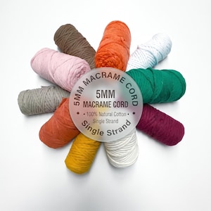May include: A collection of ten spools of 5mm single strand macrame cord in various colors including brown, orange, white, green, burgundy, yellow, rust, gray, and pink, arranged in a circle around a central label reading 5MM MACRAME CORD.