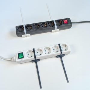 May include: A black power strip with a red switch and two white zip ties, and a white power strip with a green switch and two black zip ties. Each strip features five electrical outlets arranged in a row with attached power cords.