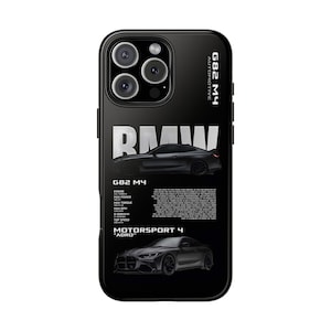 May include: A black smartphone case featuring a graphic of a BMW G82 M4 car. The design includes the text G82 M4 AUTOMOTIVE, BMW, MOTORSPORT 4 ADRO, and technical specifications. The case has a cutout for a triple-lens camera system on the back.
