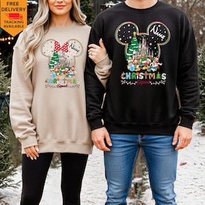 May include: A beige sweatshirt and a black sweatshirt, each featuring a graphic of a Mickey Mouse silhouette filled with a Christmas castle, a tree, and cartoon characters. The text "Name" and "Christmas Squad" are printed on both garments.
