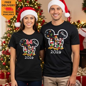 May include: Two black t-shirts featuring a white Mickey Mouse ear outline graphic containing colorful Disney characters, the text Merry Christmas, Name, and 2026. The shirts are worn with red and white Santa hats.