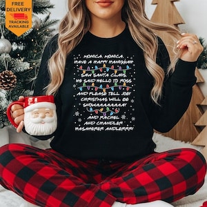 May include: A black long-sleeve sweatshirt featuring white text that reads: MONICA, MONICA, HAVE A HAPPY HANUKKAH, SAW SANTA CLAUS, HE SAID HELLO TO ROSS, AND PLEASE TELL JOEY, CHRISTMAS WILL BE SNOWAAAAAAAAY, AND RACHEL, AND CHANDLER, HASAHERER ANDLERRR.