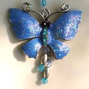 Blue sparkling butterfly pendant necklace with a partially beaded chain and dangles