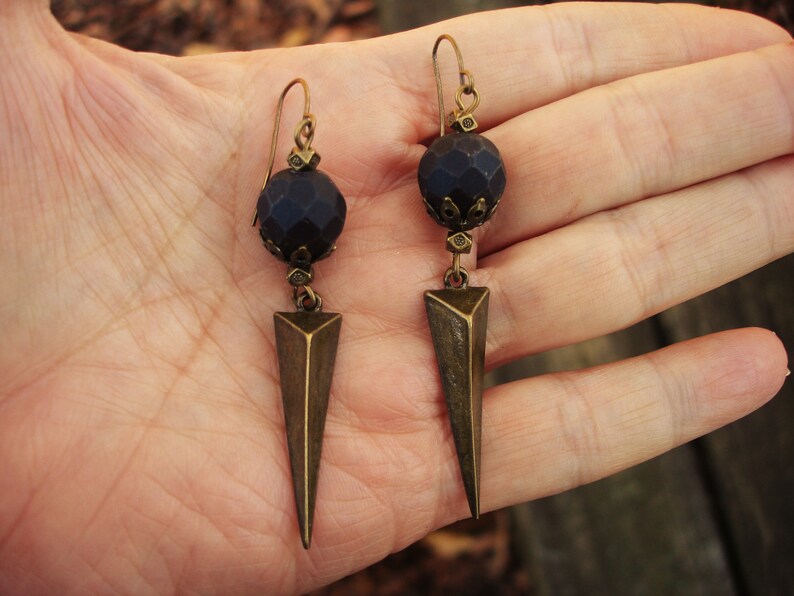 Genuine faceted black onyx matte rounds on bronze ear wires with silver plated metal triangle hollowed out spikes below.

 These earrings are about 2 3/4 inches long from the bronze ear wire.