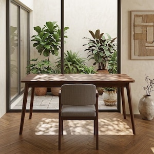 May include: A rectangular wooden dining table with tapered legs and a matching chair featuring a light gray upholstered seat and backrest. The furniture is positioned on a herringbone patterned wooden floor in front of a large glass window.