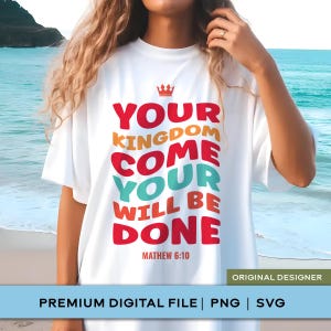 May include: A white t-shirt featuring a red crown icon above the multi-coloured text "YOUR KINGDOM COME YOUR WILL BE DONE" and "MATHEW 6:10" printed in red, orange, and teal block lettering on the front of the garment.
