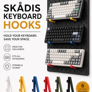 May include: A set of L-shaped plastic keyboard hooks designed for an IKEA Skådis pegboard. The hooks are shown in six colours: white, yellow, blue, red, olive green, and black. Three keyboards are mounted on a black pegboard using these hooks.