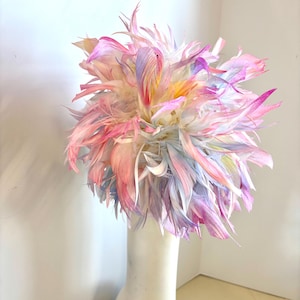 May include: A bouquet of white feathers dyed in shades of pink, blue, and yellow, arranged in a white vase.