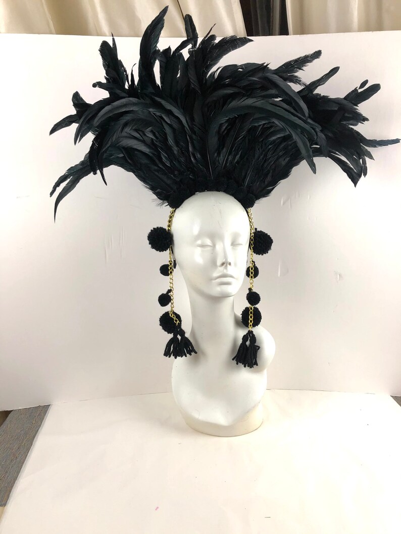 May include: Black feather headdress with black pom-poms and gold chains hanging down the sides.