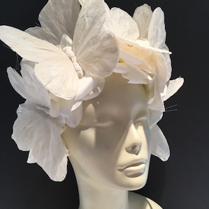 May include: A white butterfly headpiece made of fabric butterflies. The headpiece is worn on a white mannequin head.