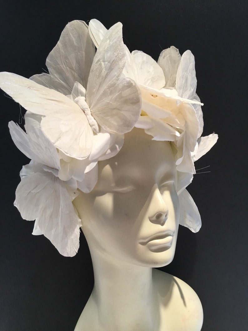 May include: A white butterfly headpiece made of fabric butterflies. The headpiece is worn on a white mannequin head.