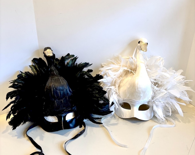 2 custom swan masks, one all white, one all black , both with gold leaf beaks
